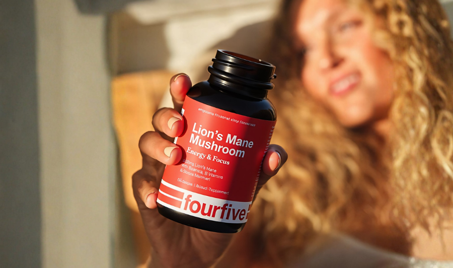 Person holding a Fourfive Lion’s Mane mushroom supplement bottle designed to support energy and focus